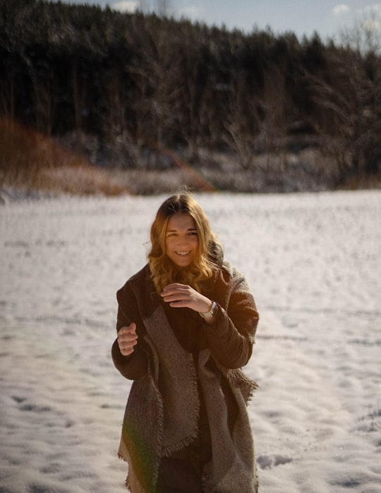woman in brown coat standing on snow covered ground during daytime in Ostoros Hungary