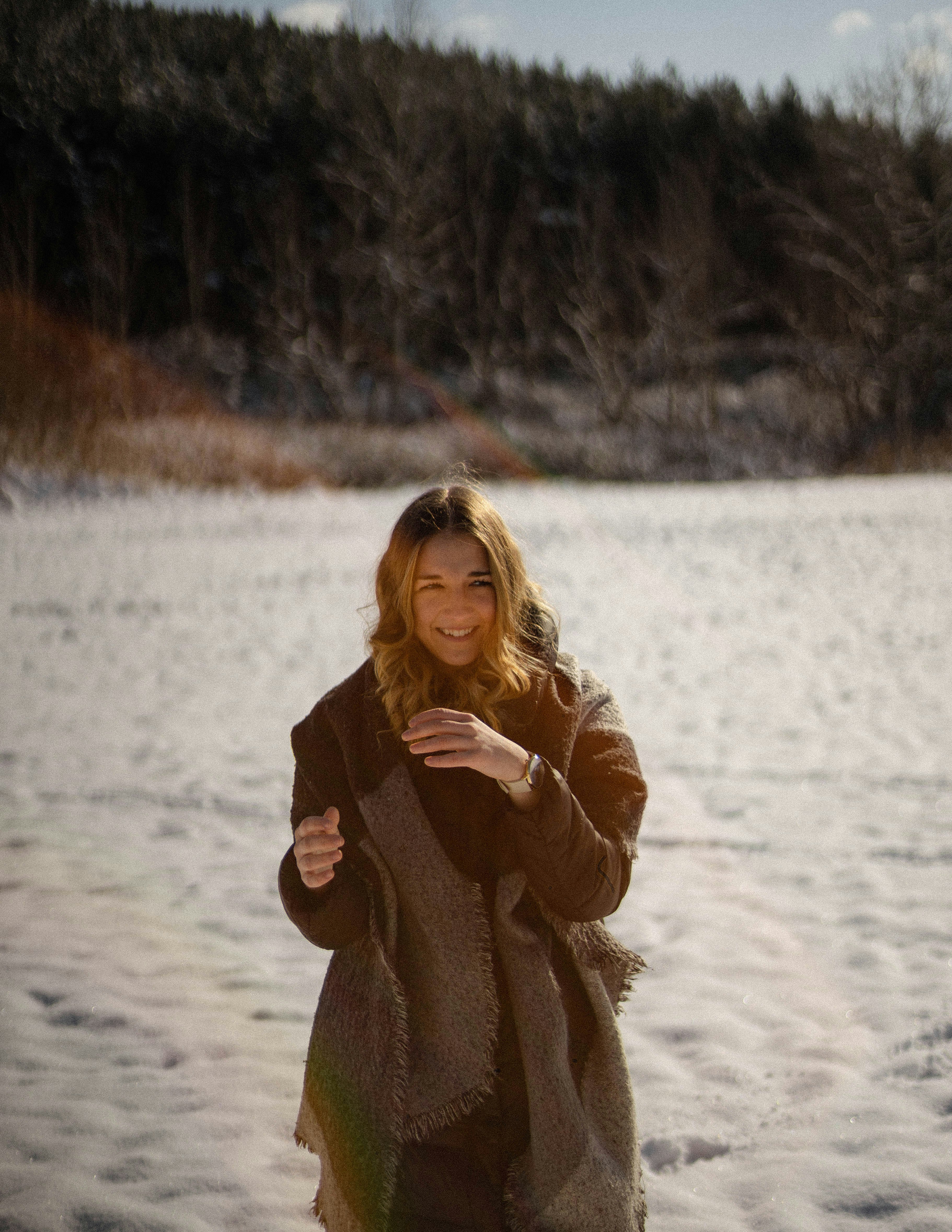 woman in brown coat standing on snow covered ground during daytime