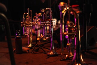 A close-up of a trombone resting on a wooden stage floor under soft warm lighting.