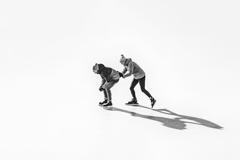 白い雪に覆われた地面でスケートボードをする2人の男性