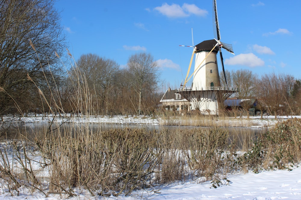 white windmill on snow covered ground under blue sky during daytime