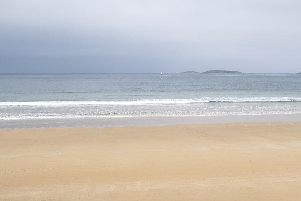 brown sand near body of water during daytime