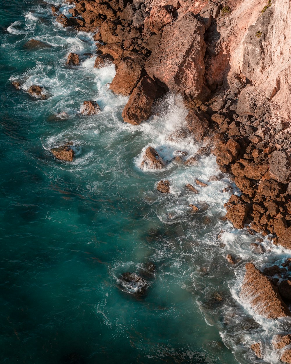 brown rocky mountain beside body of water during daytime