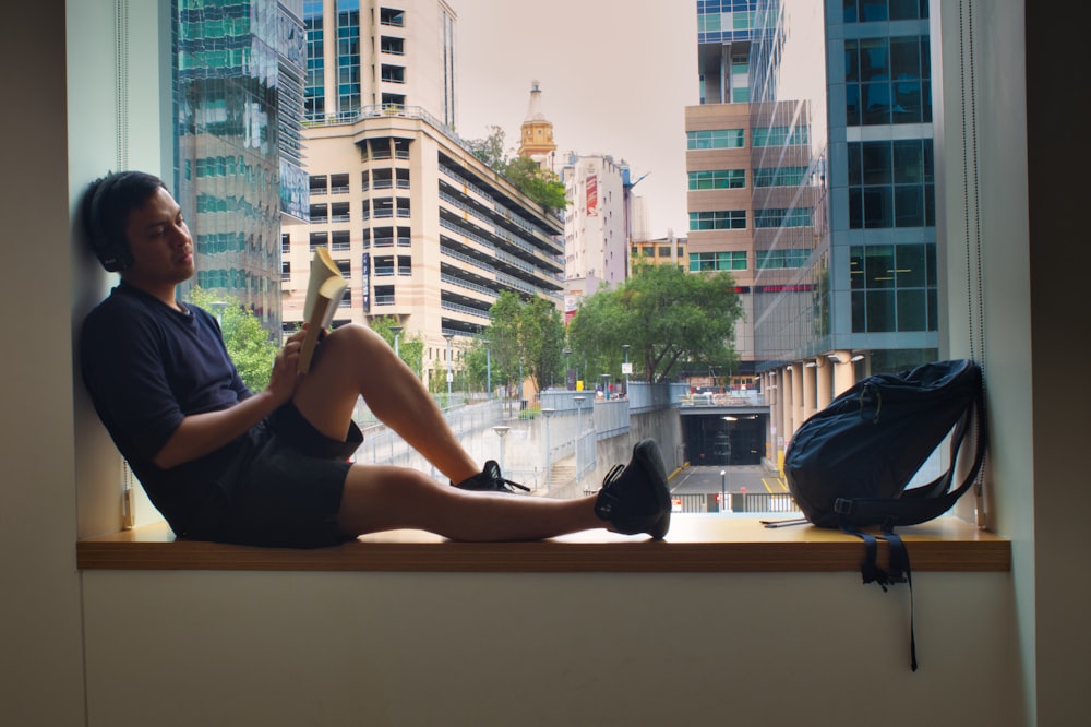 woman in black tank top sitting on window