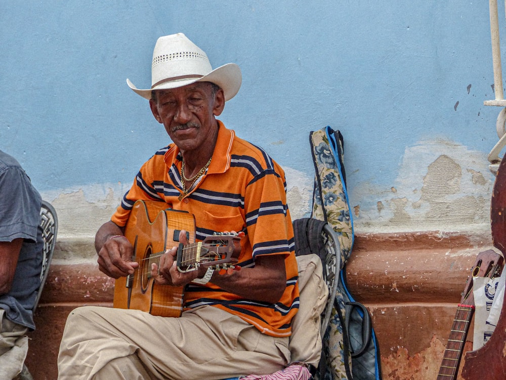 um homem sentado em um banco tocando uma guitarra