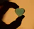 A serene close-up of hands gently holding a glowing heart-shaped crystal, resting on an open journal.