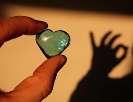 Hands holding a glowing heart-shaped light symbolizing care and hope.