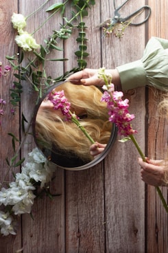 woman in pink shirt holding pink and white flowers