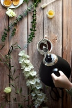 A rustic wooden table displaying raw honey, coconut oil, and coffee beans surrounded by lush green leaves.