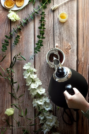A rustic wooden table displaying raw honey, coconut oil, and coffee beans surrounded by lush green leaves.
