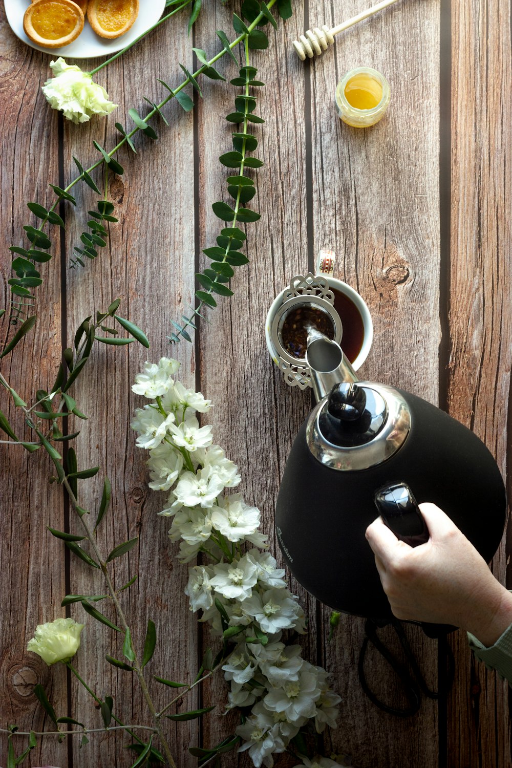 person holding black ceramic teapot