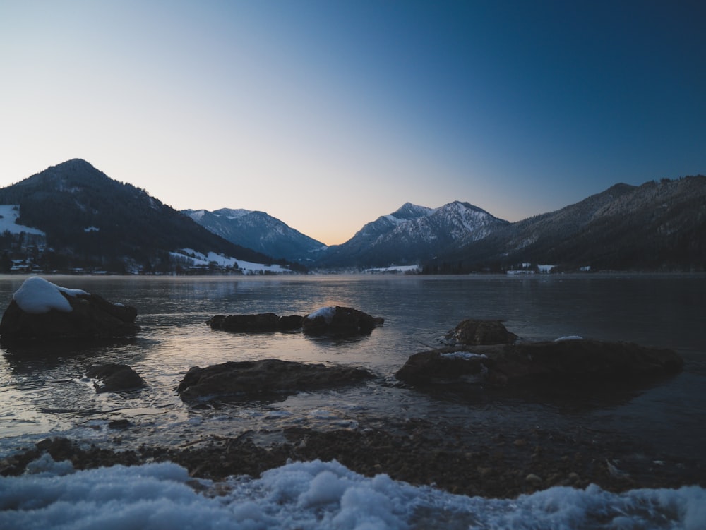 body of water near mountain under blue sky during daytime