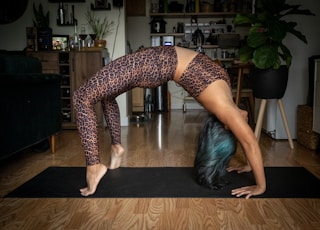 woman in black and white polka dots leggings bending her body on brown wooden table