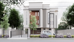 A modern, multi-story building with a minimalist design features large vertical windows and accent walls with wooden panels. The property is surrounded by a metal fence with a gate, and there are street lamps and tall trees along the perimeter. A car is parked inside the gated area, and the landscaped front garden is adorned with shrubs and plants.