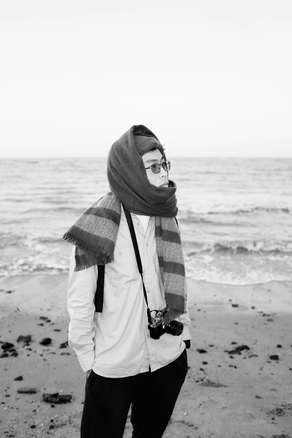 woman in white coat and red and black scarf standing on beach during daytime