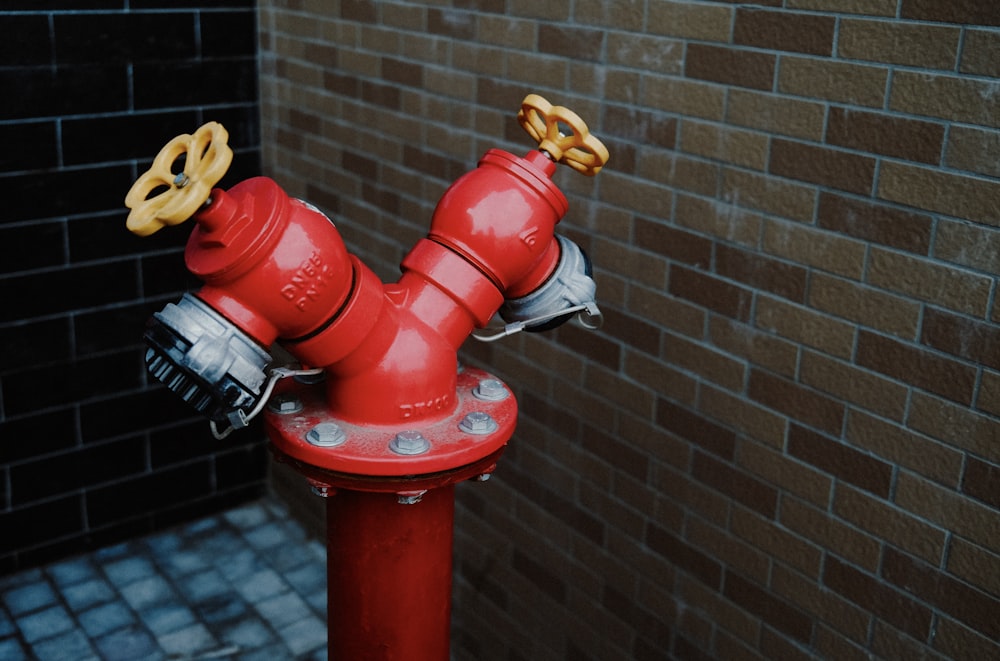 hidrante vermelho perto da parede de tijolos marrons