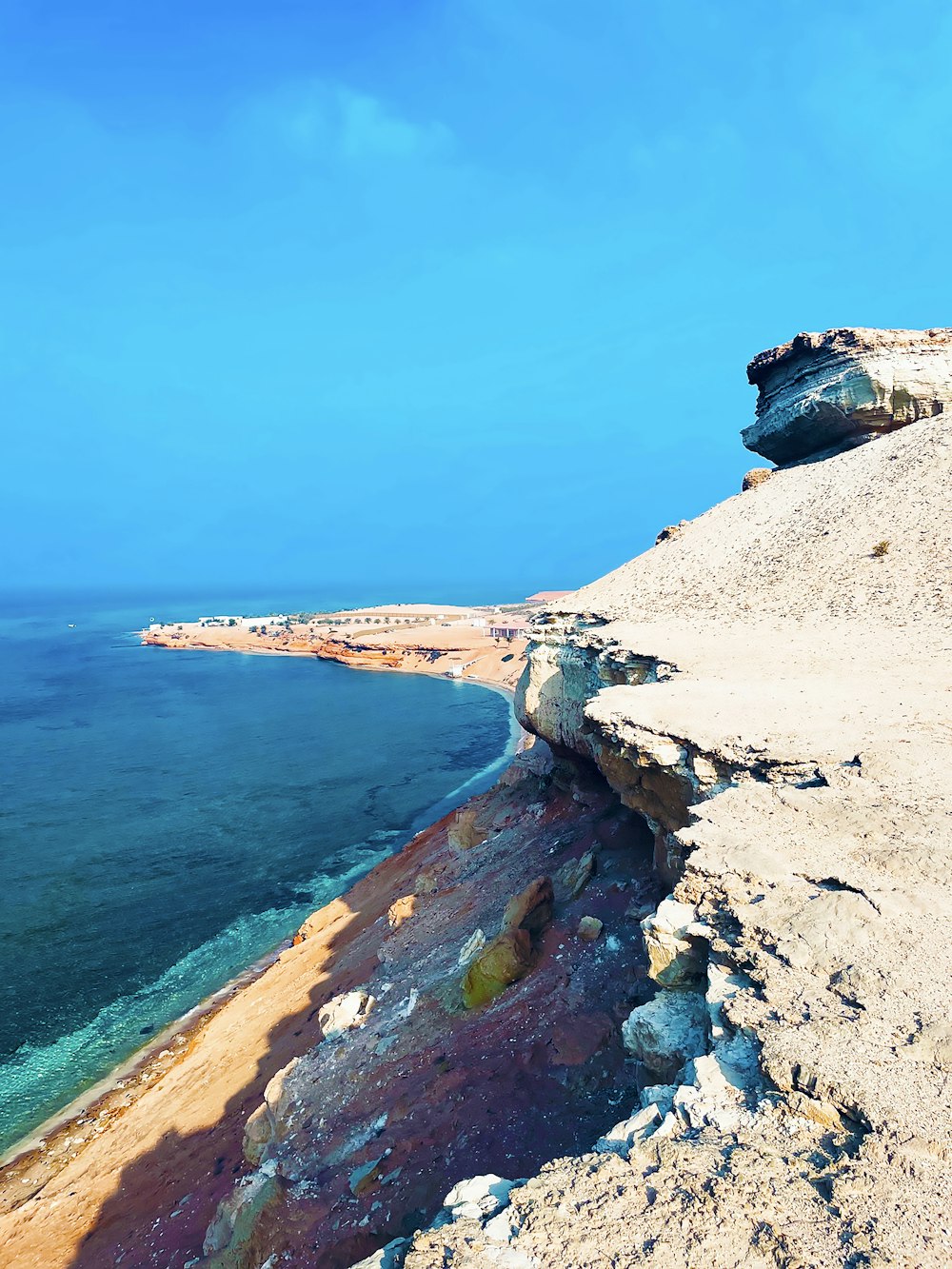 brown rocky mountain beside blue sea under blue sky during daytime