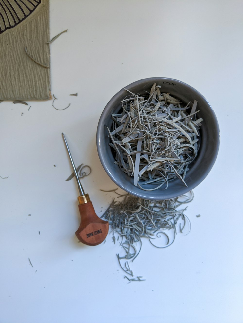 silver and orange handle scissors on gray round bowl