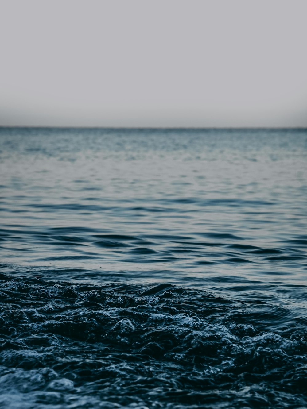 water waves under white sky during daytime