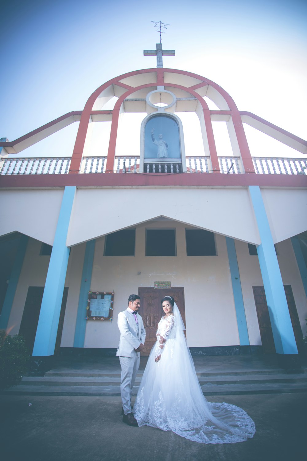 a bride and groom standing in front of a church