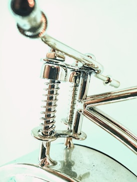 Close-up view of a metallic object featuring a highly polished chrome finish, including coiled springs and smooth cylindrical components connected by sleek rods.