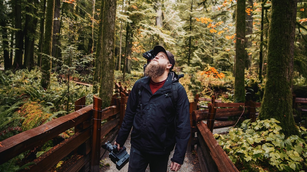 man in black jacket standing on wooden bridge