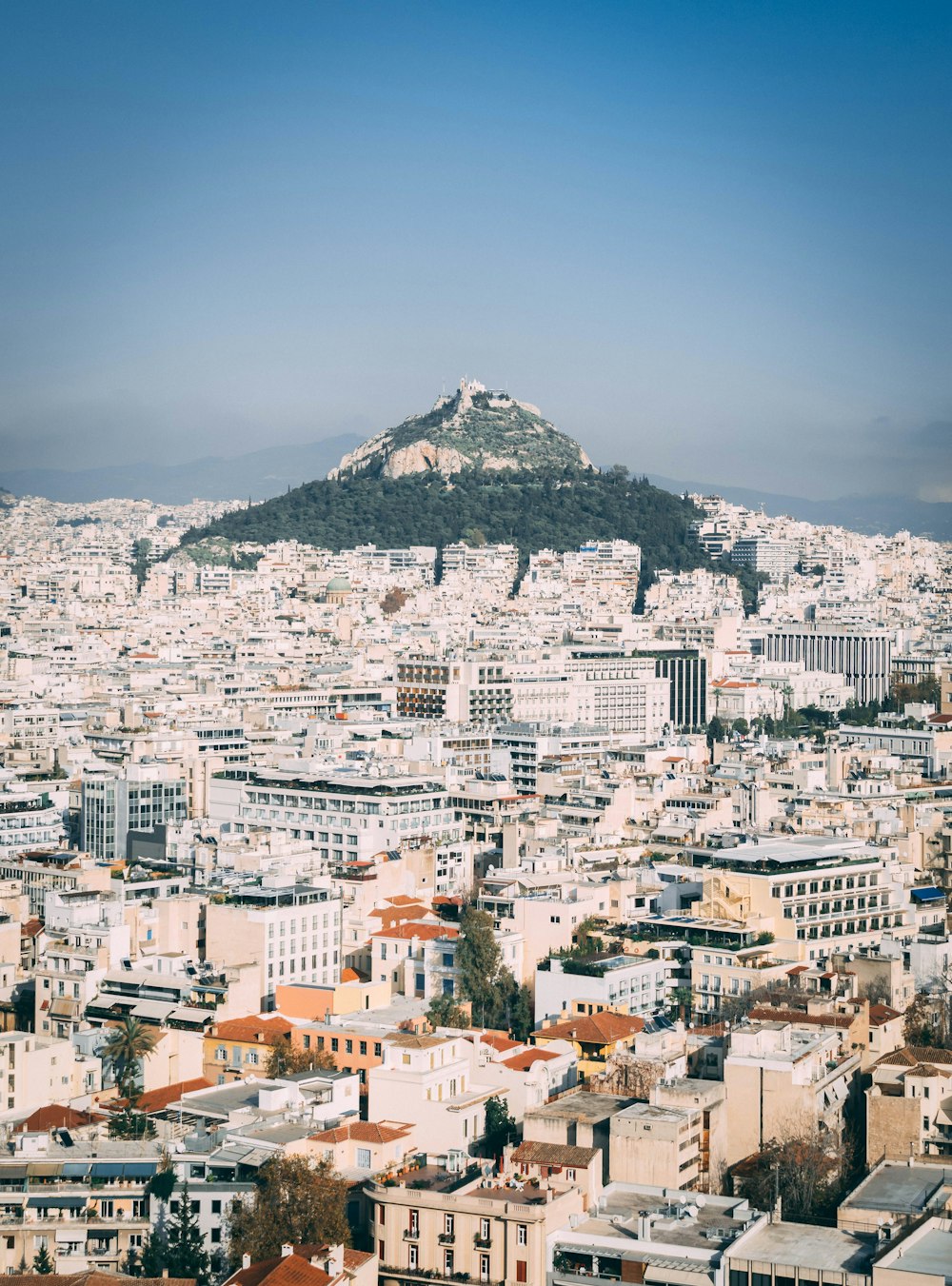 white and brown concrete buildings near mountain under blue sky during daytime