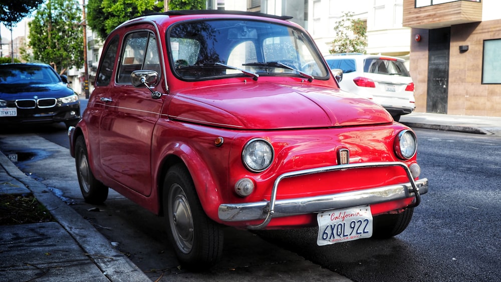 red volkswagen beetle parked on sidewalk during daytime