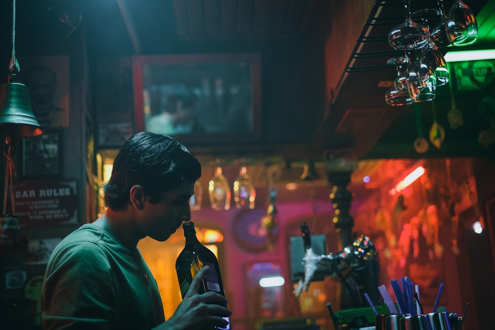 man in green dress shirt holding bottle