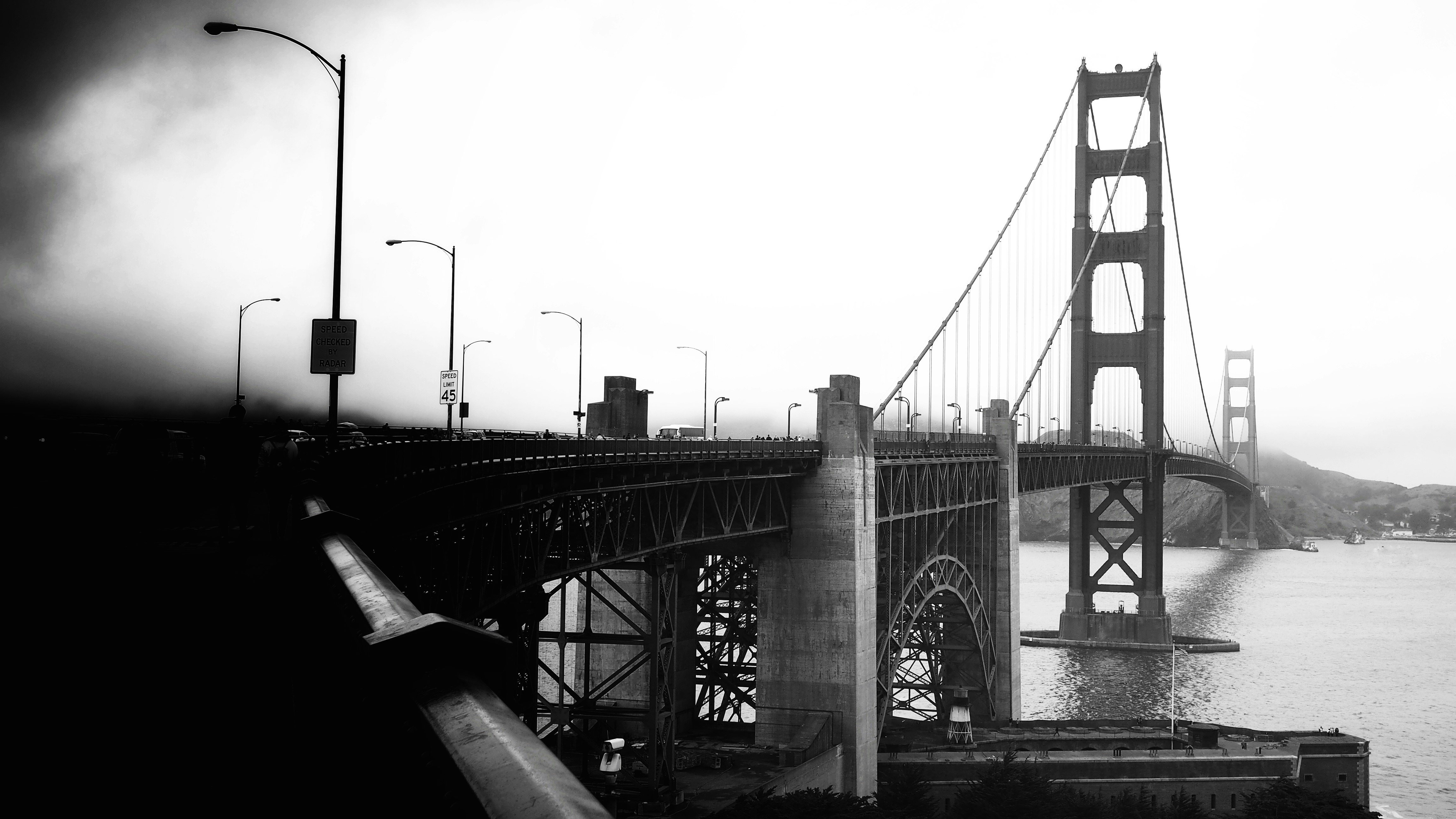 grayscale photo of bridge under cloudy sky