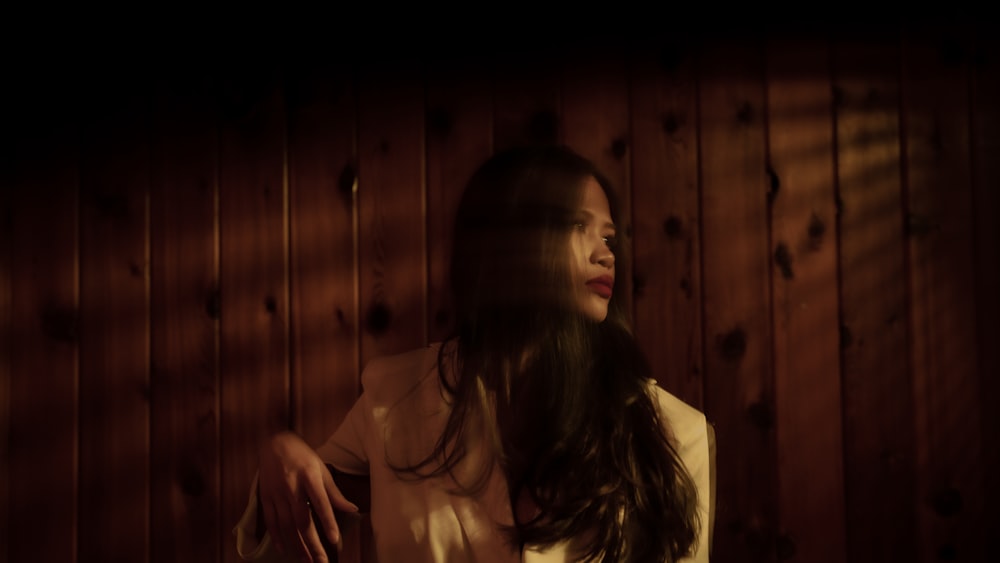 woman in white shirt standing near brown wooden wall