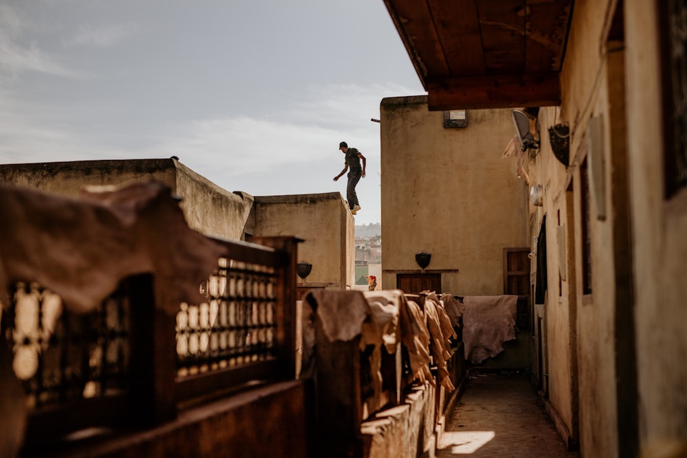 man jumping on brown wooden fence during daytime