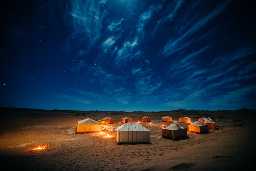 밤 시간 동안 푸른 하늘 아래 갈색 들판에 흰색과 갈색 텐트