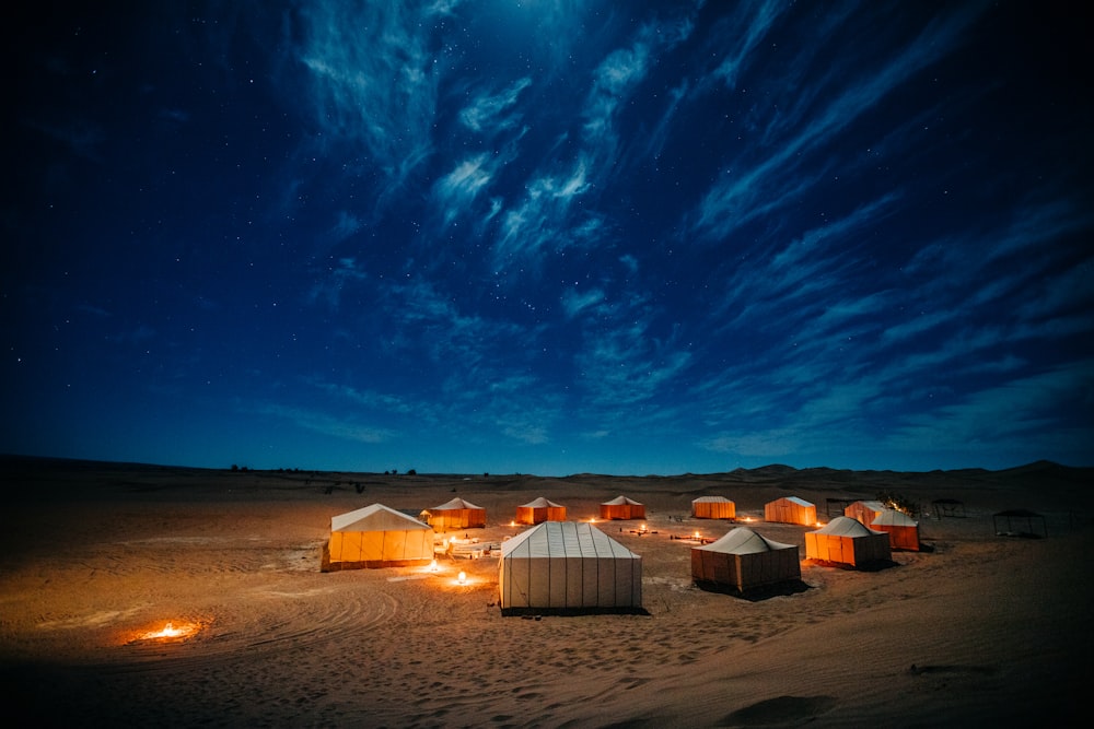 Tente blanche et brune sur un champ brun sous un ciel bleu pendant la nuit