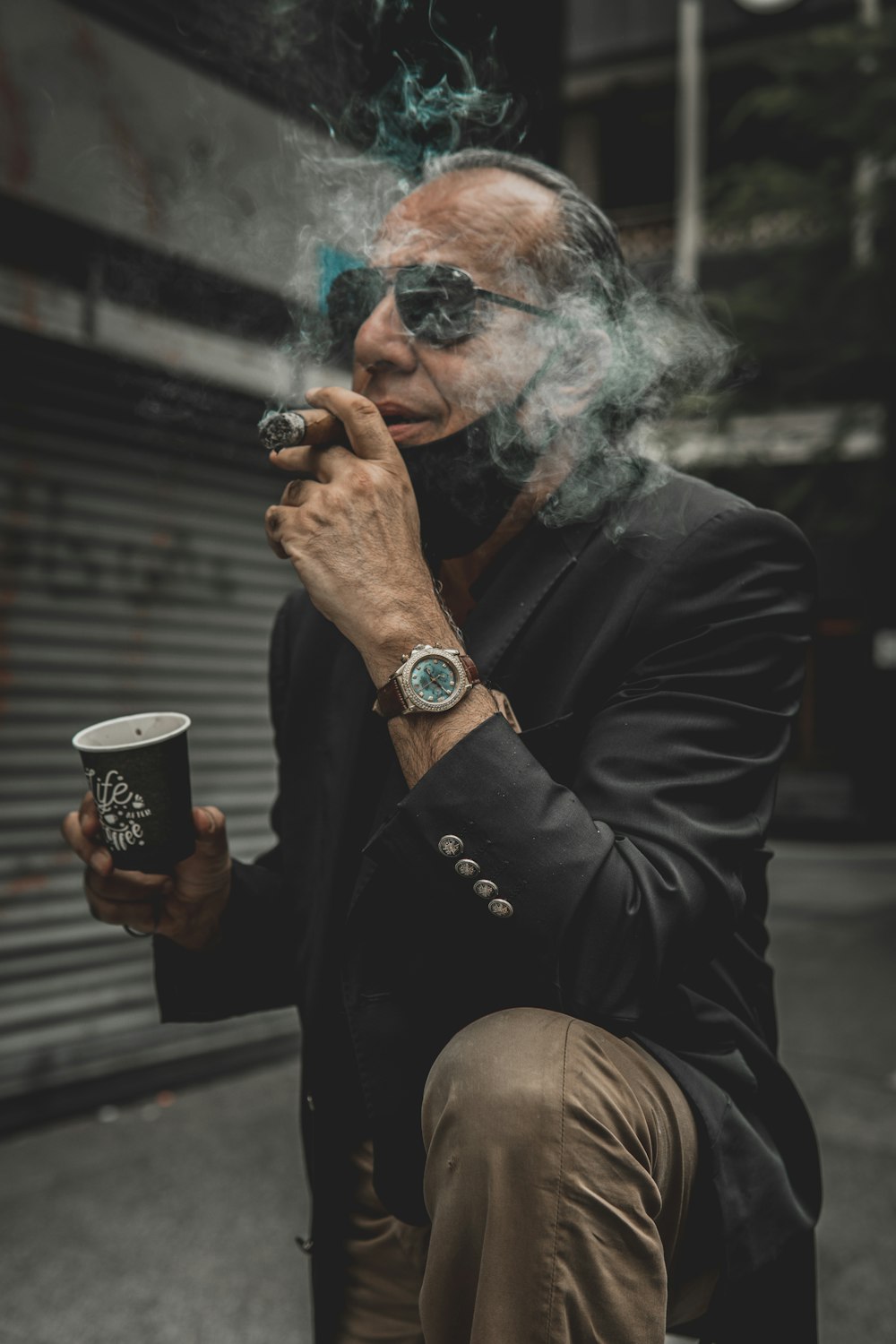 man in black coat holding black and white ceramic mug