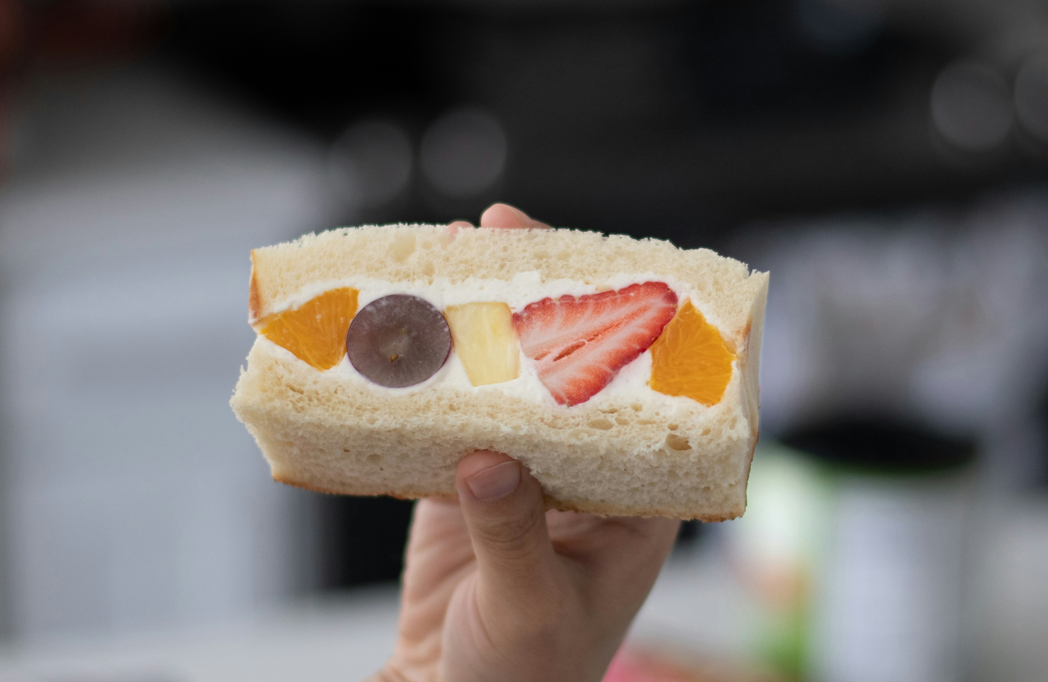 person holding bread with red and white cream