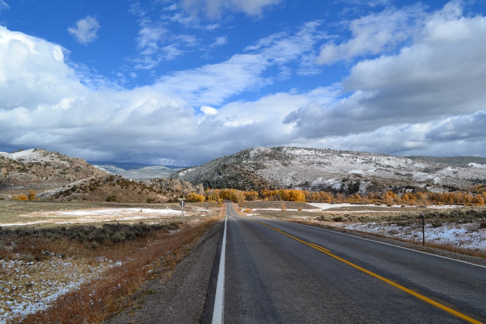 gray concrete road under blue sky and white clouds during daytime