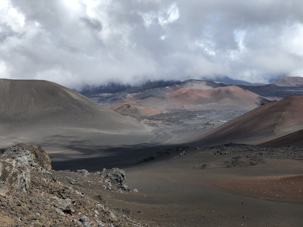 montañas marrones y grises bajo nubes blancas y cielo azul durante el día