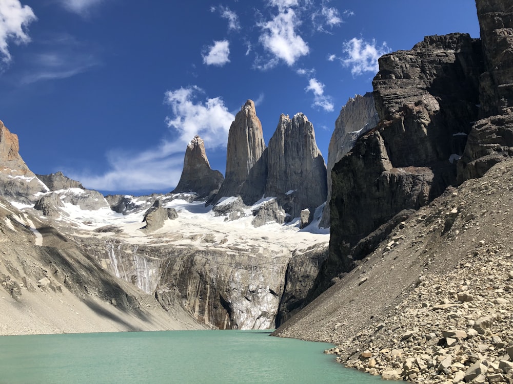 Montagne rocheuse brune à côté d’un plan d’eau sous un ciel bleu pendant la journée