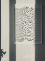 Minimalist line art of a mountain range in black and white, framed in a thin wood frame, hanging above a modern console table.