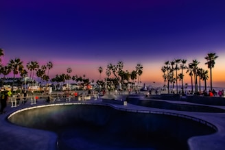 A colorful cruiser board parked near a beach boardwalk at sunset.