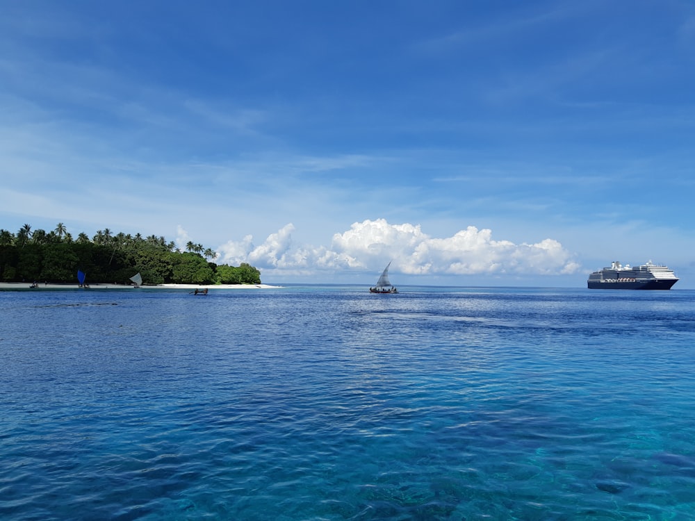 green trees on island surrounded by sea under blue and white cloudy sky during daytime