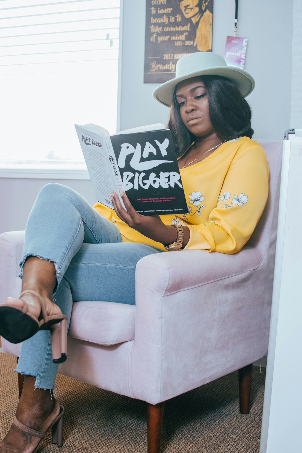 woman in yellow hoodie and blue denim jeans sitting on gray sofa chair