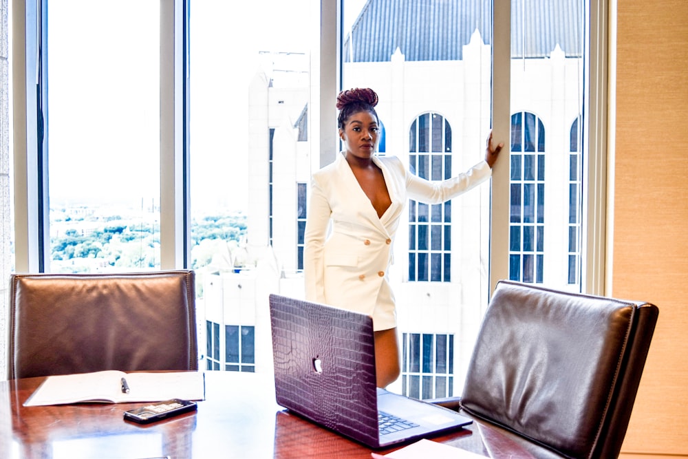 woman in white blazer standing near window