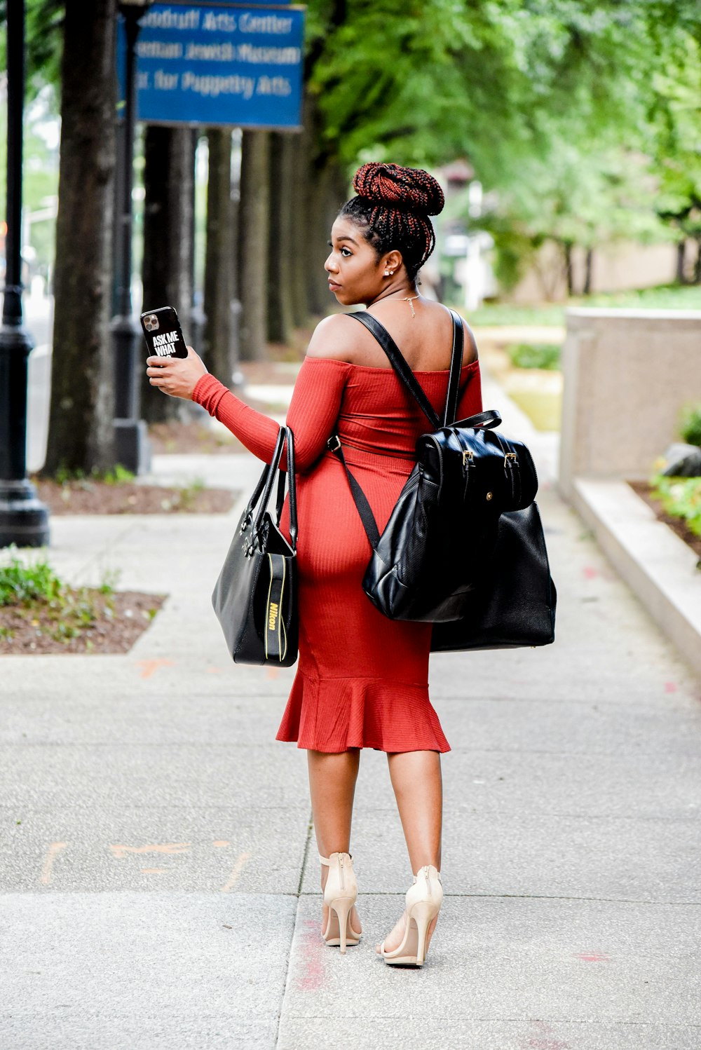 Donna in vestito nero e rosso che tiene la borsa a tracolla di pelle nera