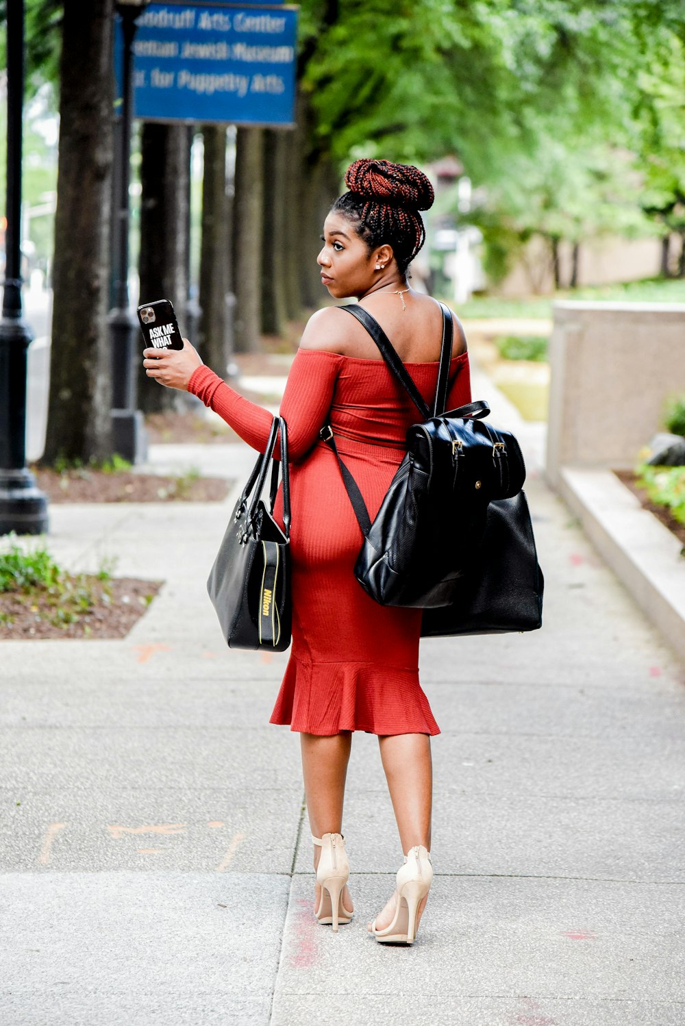 femme en robe noire et rouge tenant un sac à bandoulière en cuir noir