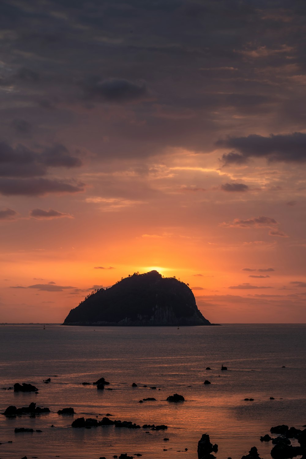 silhouette of island on sea during sunset