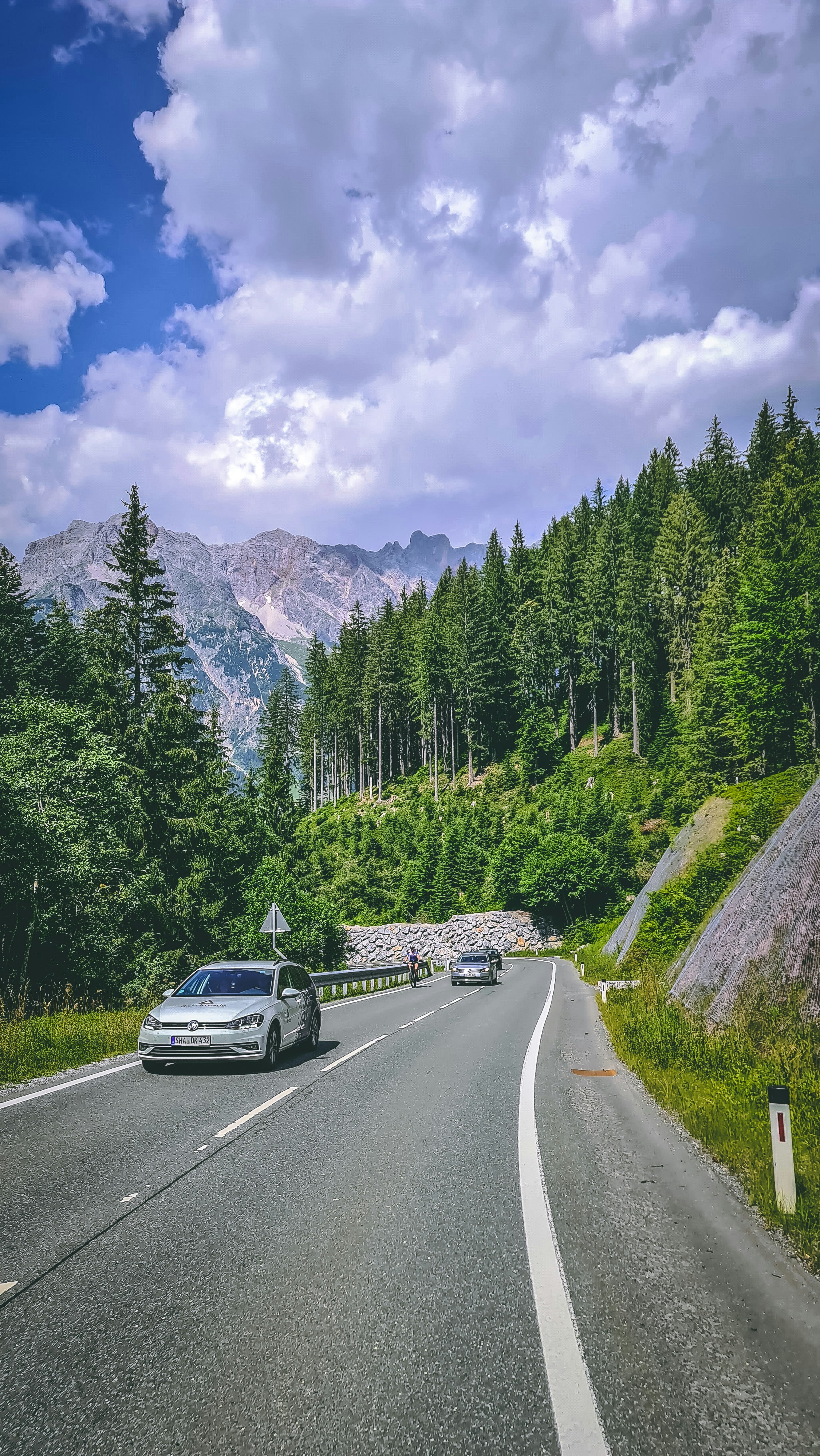 Foto zum Thema Schwarzes Auto auf der Straße in der Nähe von grünen Bäumen und Bergen unter