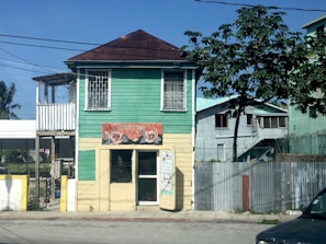 white and green wooden house near green tree under blue sky during daytime