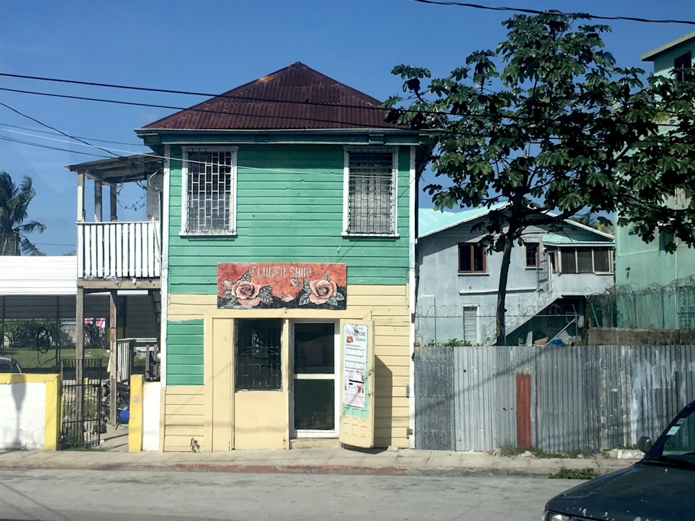 white and green wooden house near green tree under blue sky during daytime